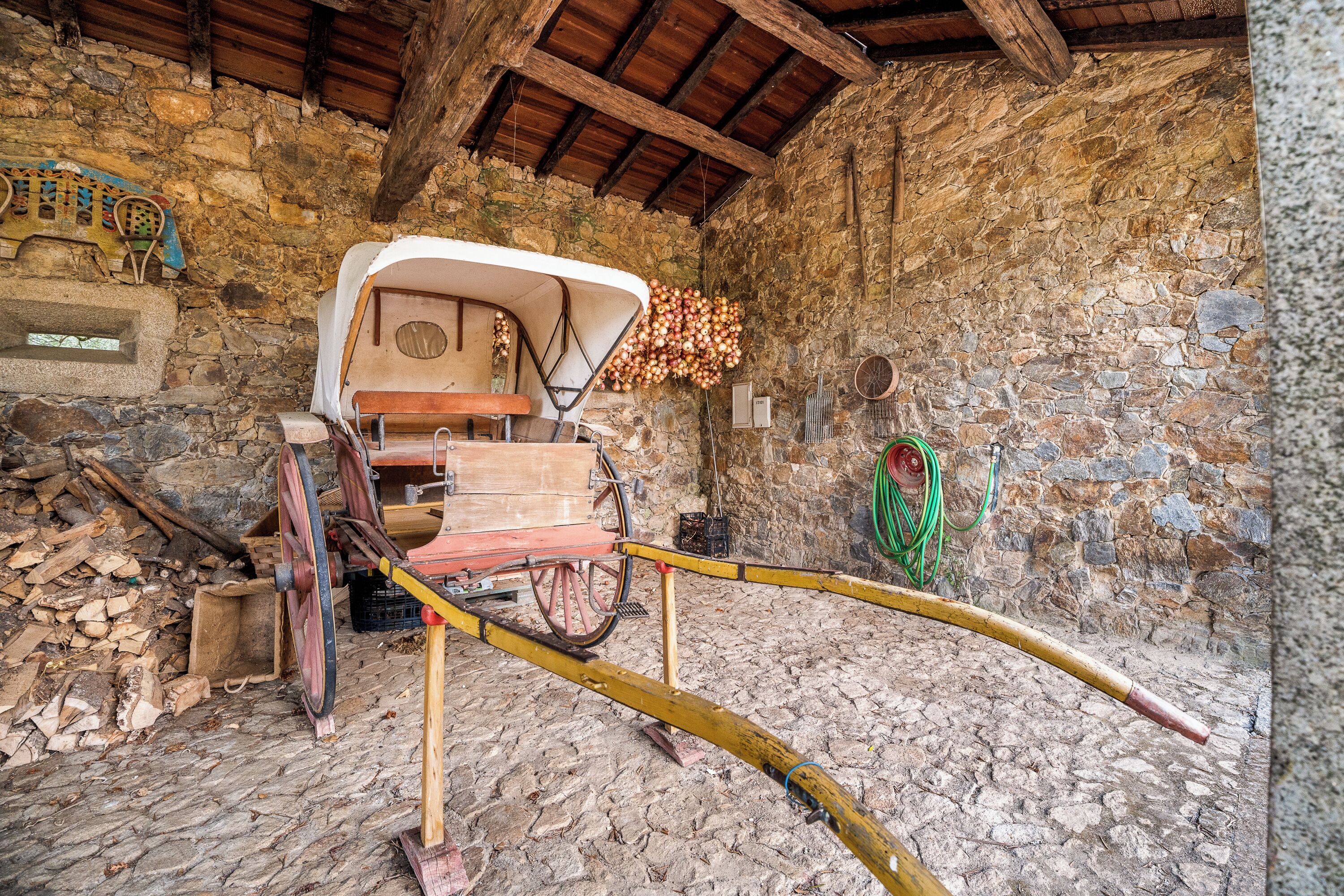 Ein rustikales Interieur mit einem Holzwagen, Steinwänden und einem Steinfußboden.