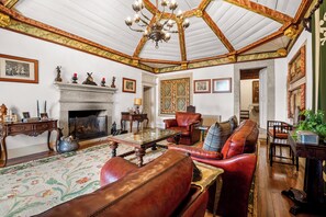 A traditional room with a fireplace, leather furniture, and a chandelier. - Casa Do Anquião (Ponte de Lima)
