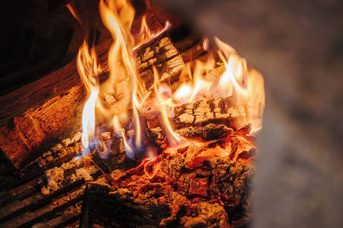 A close-up of a fire burning in a fireplace with visible logs and flames.