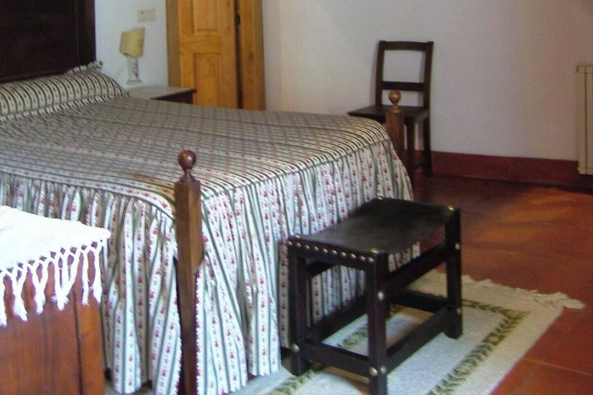 A bedroom with a wooden staircase, a bed with a patterned bedspread, a chair, and a small table.