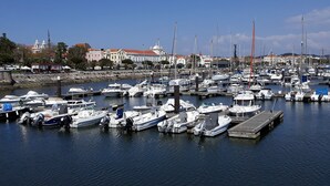 A marina with numerous boats docked, a waterfront promenade, and buildings in the background. - Hotel Aliança (Figueira da Foz)