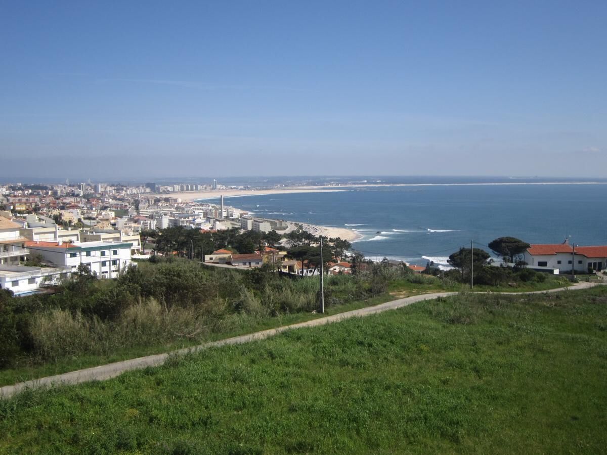 A coastal cityscape with buildings, a beach, and a clear sky.