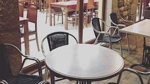 A restaurant with multiple tables and chairs, a stone wall, and a view into the dining area.