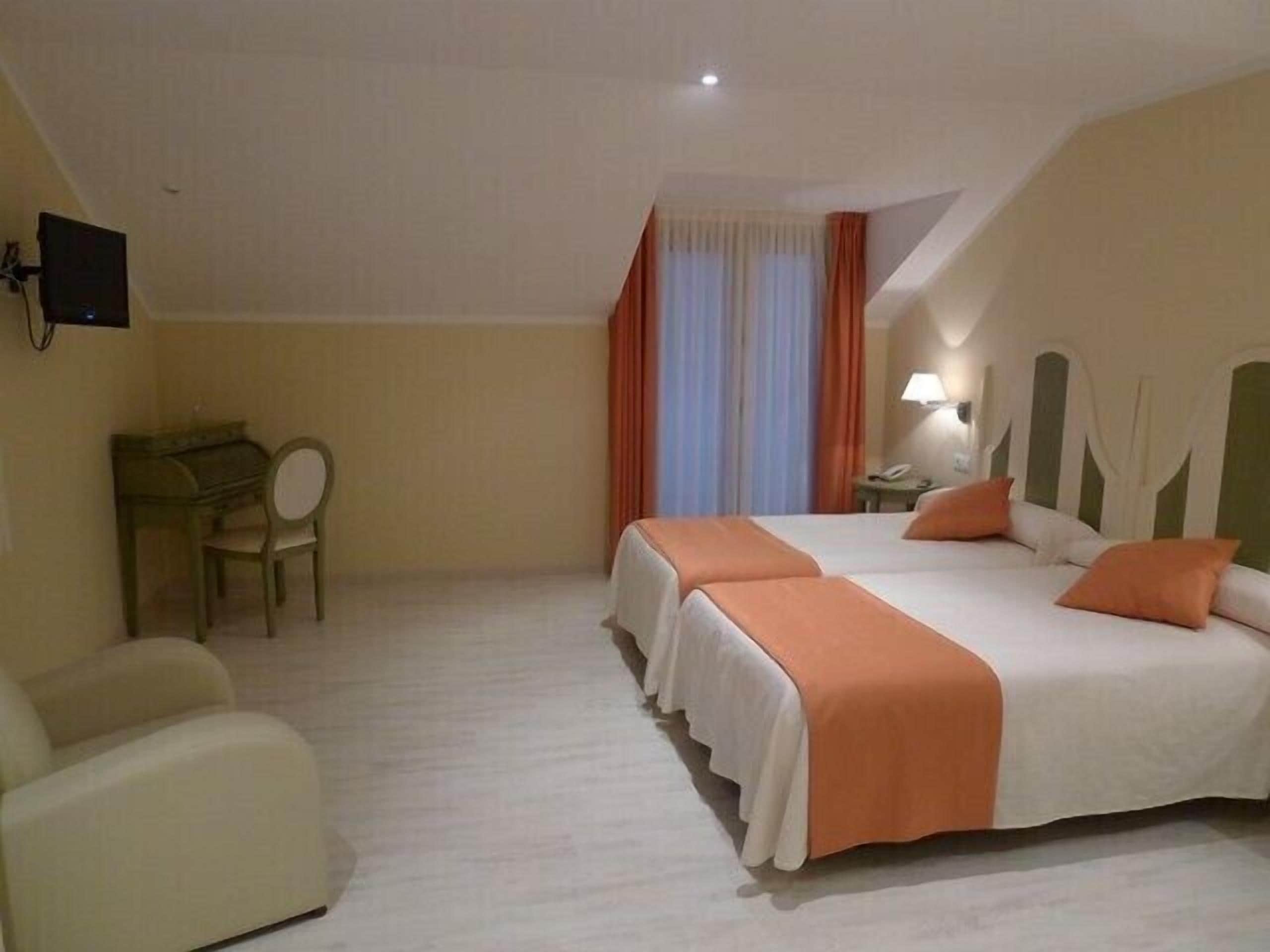 Une chambre d’hôtel avec deux lits, un bureau, une chaise et un téléviseur.