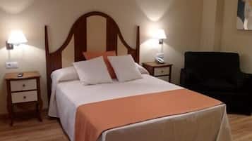 Una habitación de hotel con una cama grande, dos mesitas de noche con lámparas, una silla y un cuadro en la pared.
