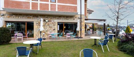 A building with a stone facade and a patio area with outdoor seating.