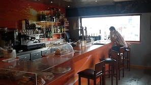 A bar area with a counter, stools, and shelves stocked with bottles.