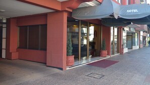 A hotel entrance with a glass door, a red exterior, and a covered awning. - Hotel Don Eduardo (Temuco)