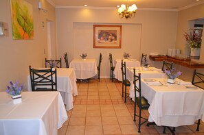 Zona pranzo con diversi tavoli e sedie, un lampadario e opere d'arte appese alle pareti.