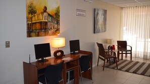 A business center with a desk, two monitors, a lamp, and a chair. - Hotel Don Eduardo (Temuco)