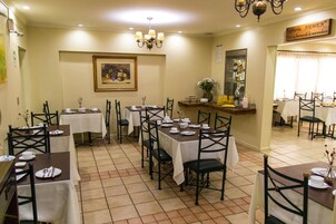 Un restaurante con varias mesas y sillas, un cuadro en la pared y un letrero sobre la barra.