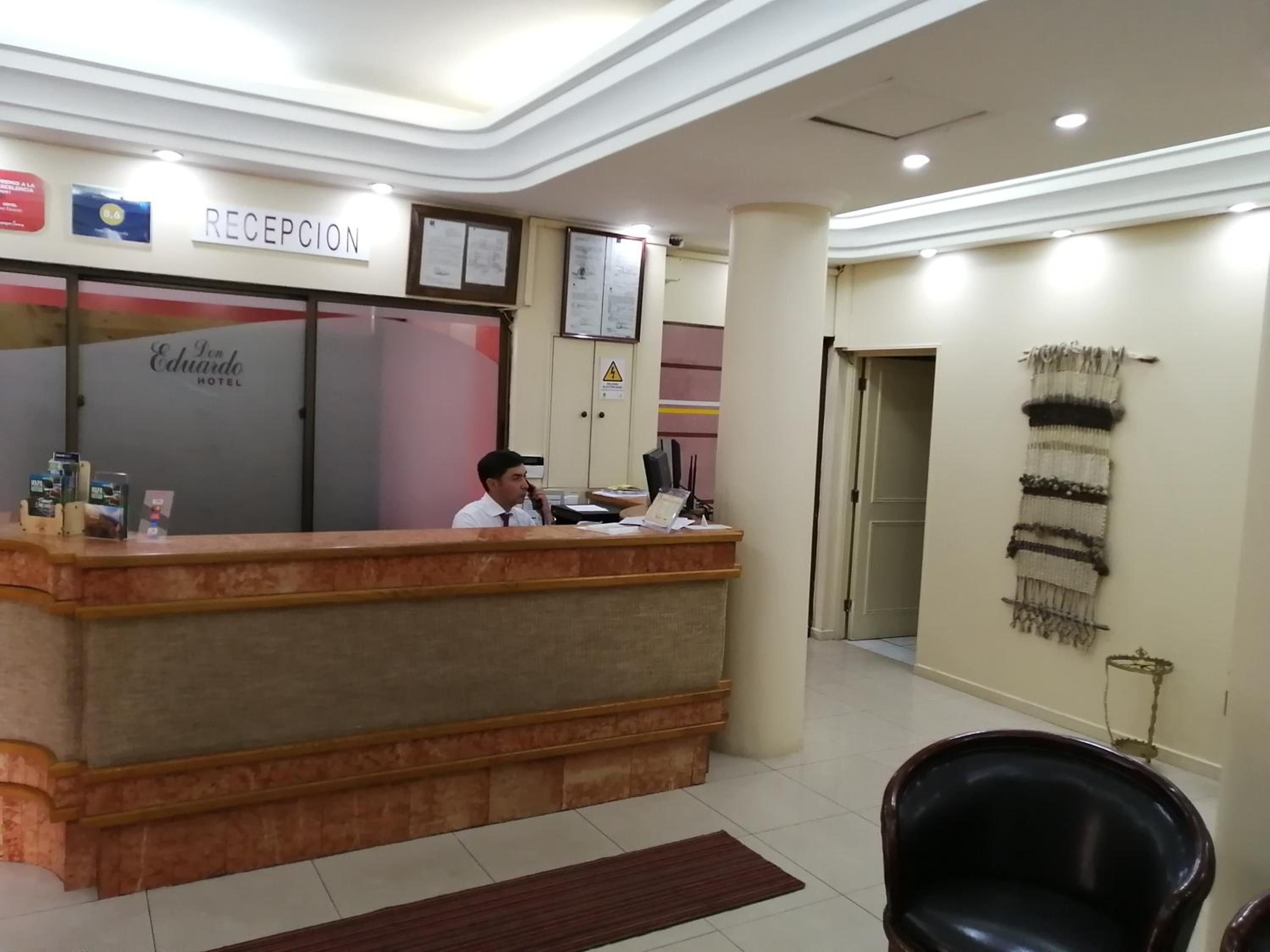 Un taulell de recepció amb un rètol a la part superior, un telèfon fixat a la paret i un certificat o avís emmarcat.