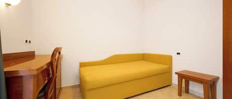 A room with a yellow sofa, wooden dining table, and chairs.