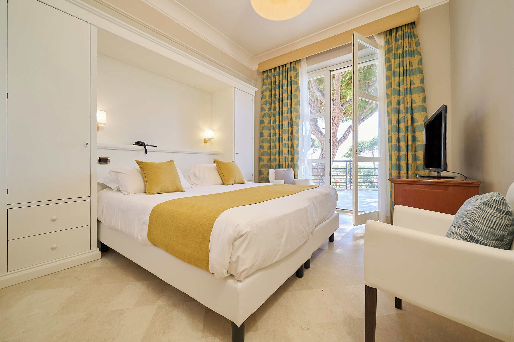 A hotel room with a bed, a TV, a desk, and a chair.
