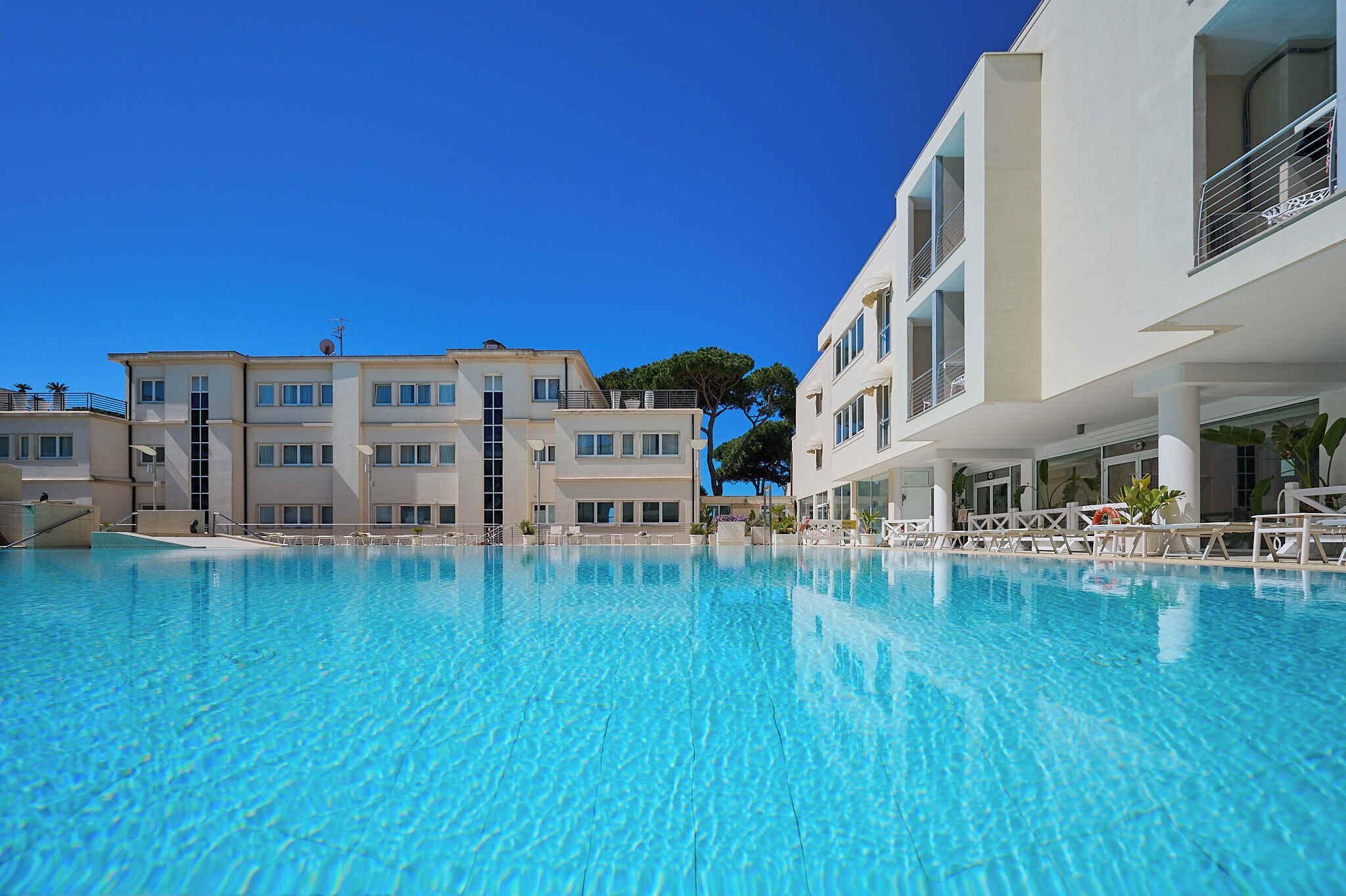 Une piscine d’un bleu éclatant, avec un bâtiment moderne en arrière-plan.