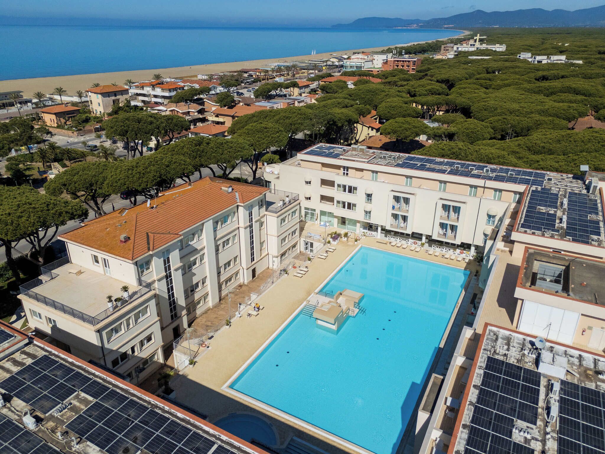 A hotel with a swimming pool, solar panels, and a view of the beach.