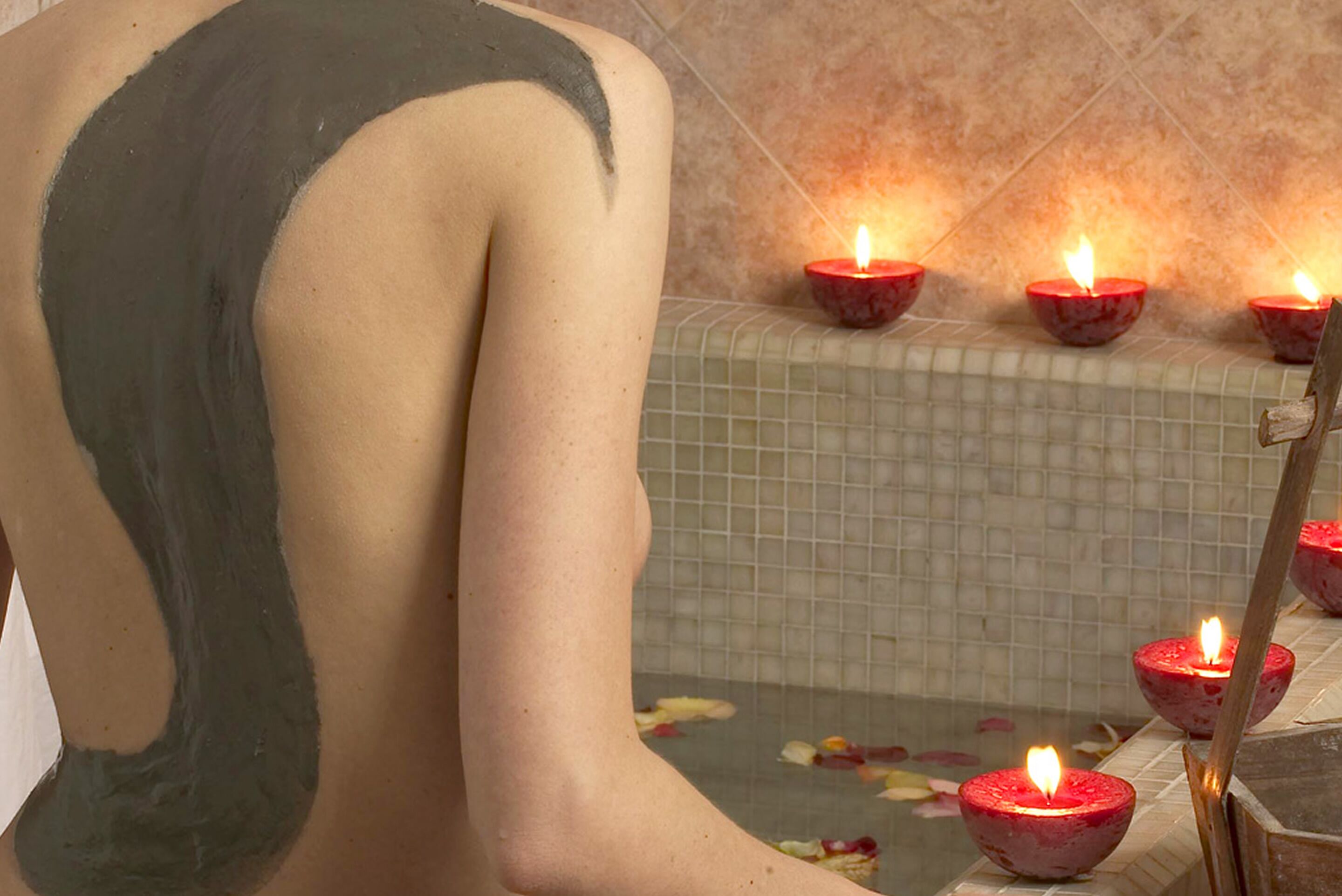 Uma banheira com velas e uma parede azulejada.