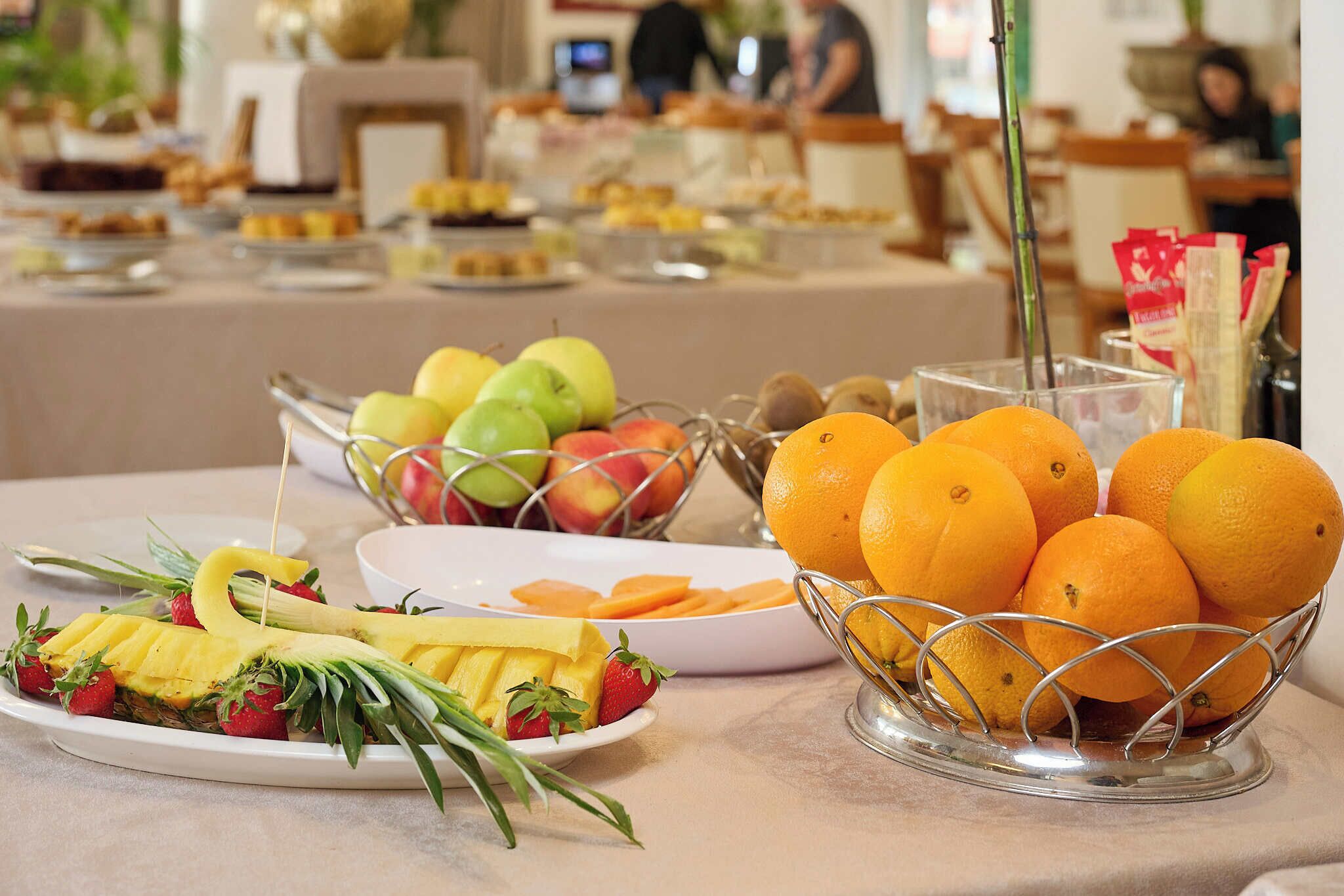 A buffet table with various fruits and a coffee station.