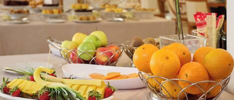 A buffet table with various fruits and a coffee station.