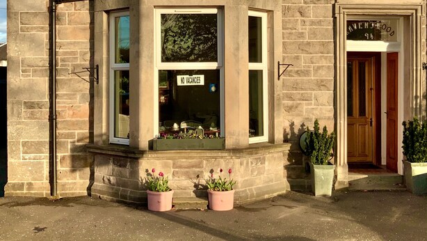 A stone building with a 'NO VACANCIES' sign, a shop entrance, and a sign reading 'AVENUEWOOD 94'. - Ravenswood Guest House (Stirling)