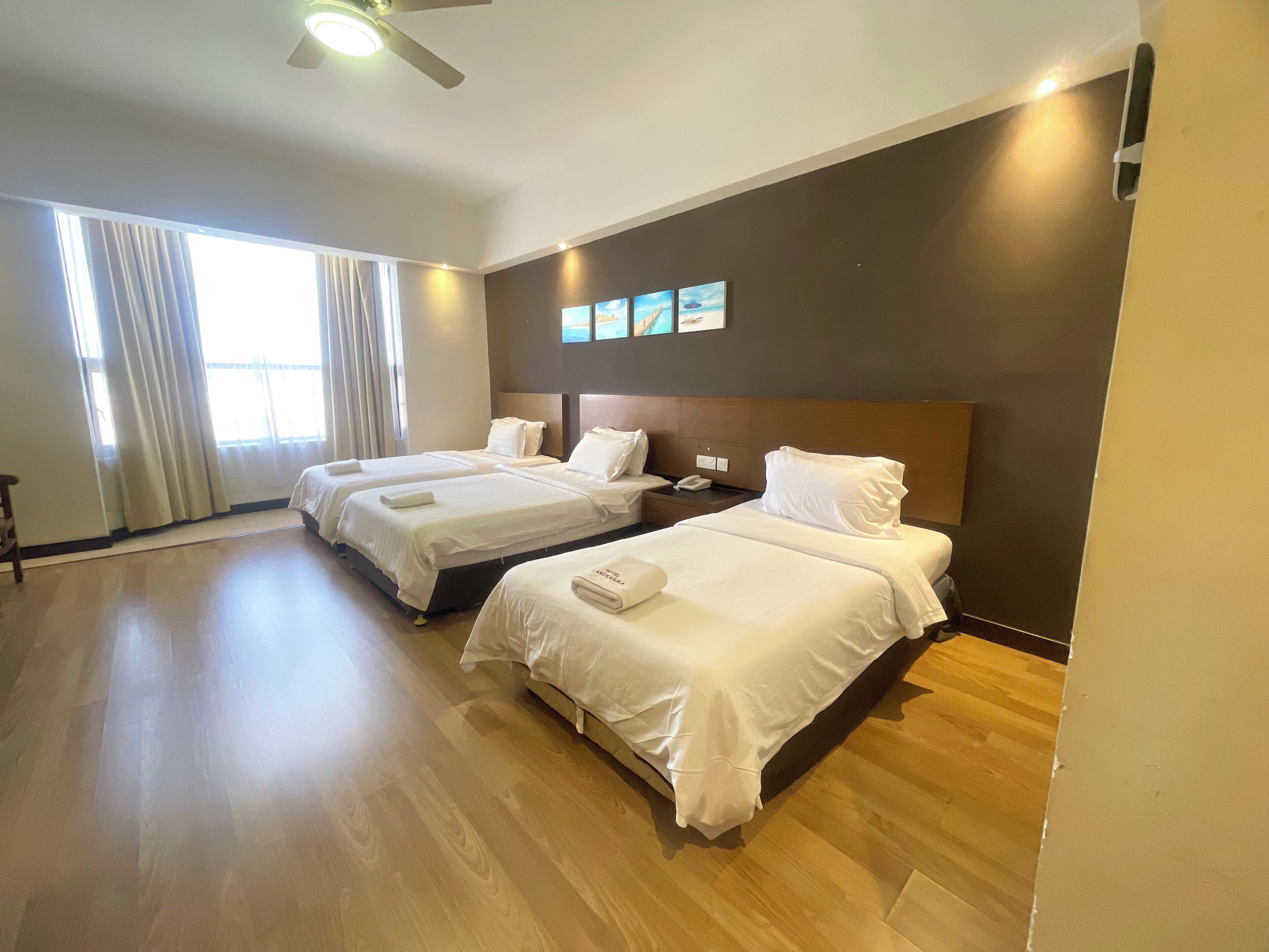Habitación de hotel con dos camas, una mesita de noche, un teléfono y una ventana con cortinas.