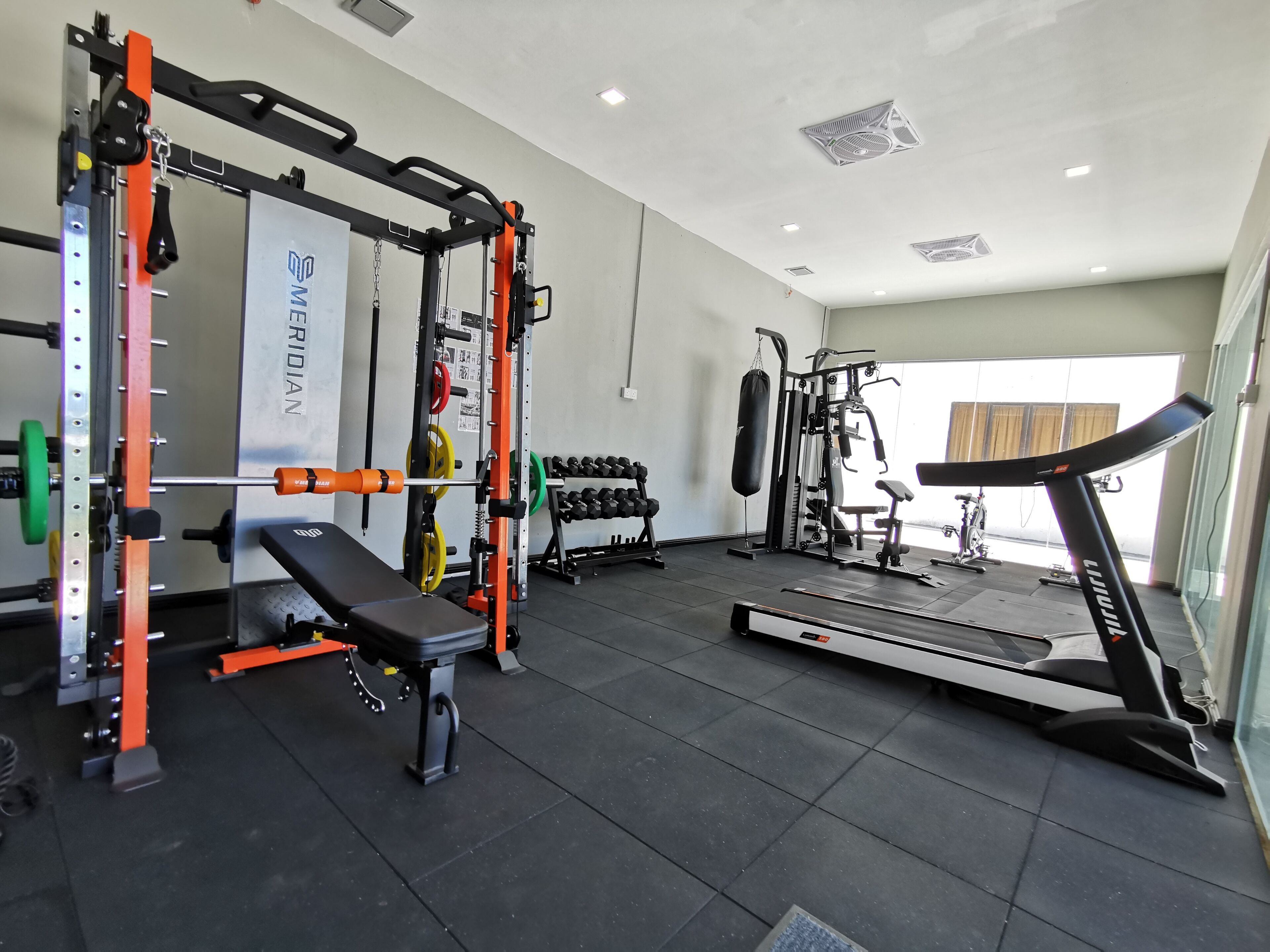 A gym with weightlifting equipment, a bench, dumbbells, and a treadmill.