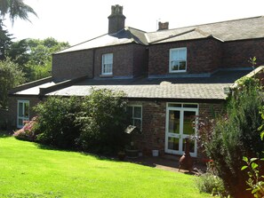 A two-story brick house with a sloped roof, a front porch, and a well-maintained lawn. - Marton Grange Country House (Bridlington)