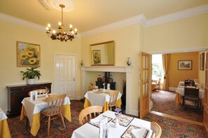 A dining room with a fireplace, yellow walls, and a chandelier. - Marton Grange Country House (Bridlington)