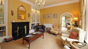 Una sala de estar tradicional con chimenea, candelabro y muebles clásicos.