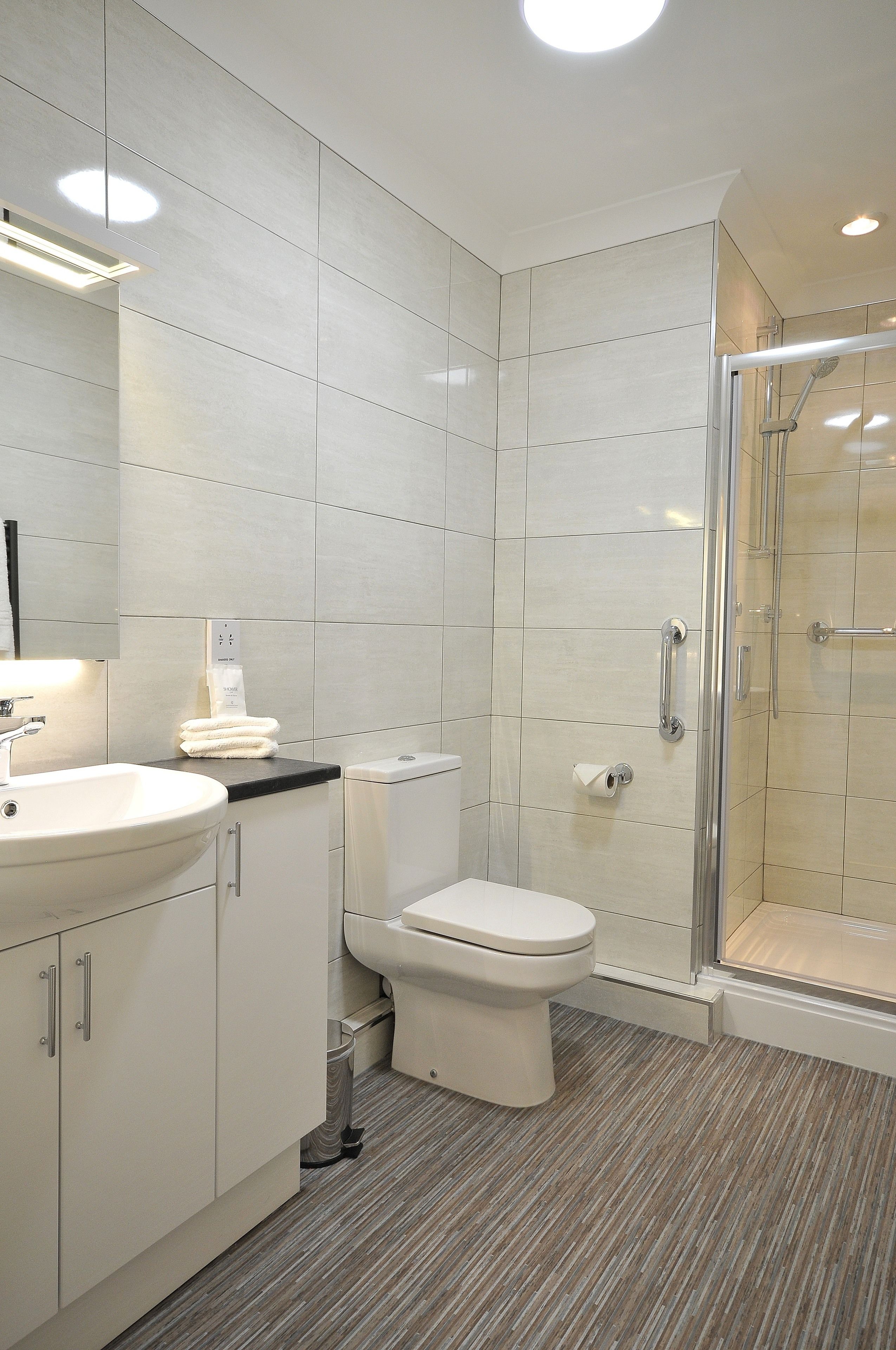 A modern bathroom with a sink, toilet, and glass shower enclosure.
