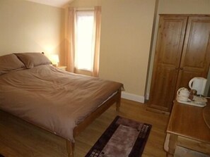 A bedroom with a bed, wooden wardrobe, and a small table with a kettle. - Park Lodge B&B (Ryde)