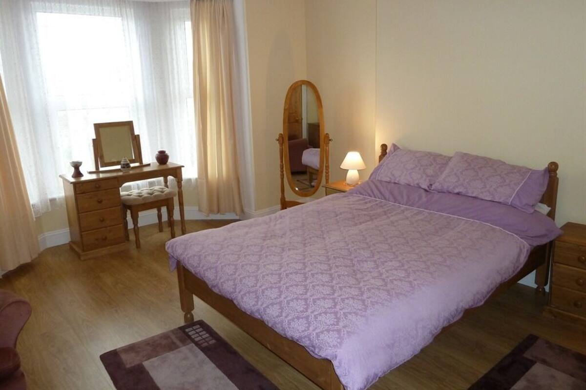 A bedroom with a bed, a dresser, a mirror, and a desk with a chair.