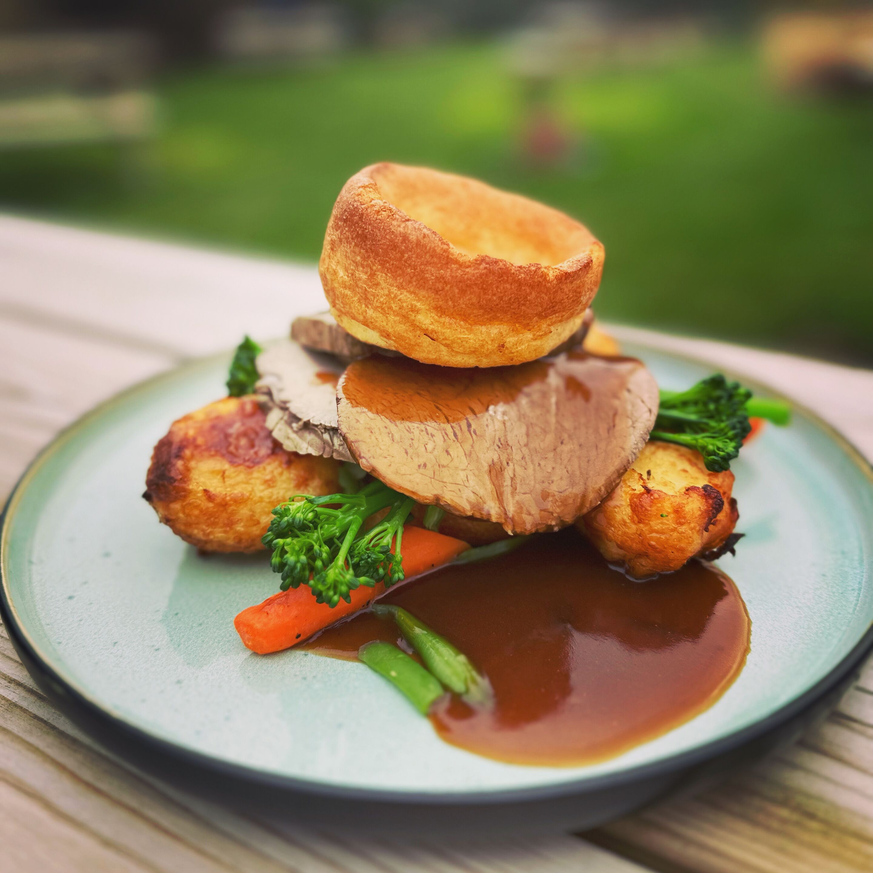 A plate of food with a Yorkshire pudding, meat, and vegetables.