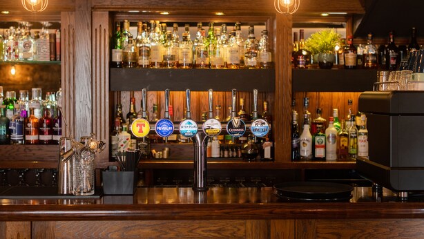 A bar with multiple taps, shelves of liquor bottles, and a decorative metal sculpture. - Smiddy Haugh (Auchterarder)