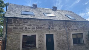 A stone building with a sloped roof, skylights, and a door. - Smiddy Haugh (Auchterarder)