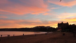 A beach with people walking along the shore, a bird flying in the sky, and buildings in the background. - St Michael's Guest House (Scarborough)