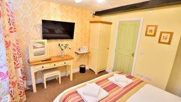 Una habitación de hotel con una cama, un escritorio con una silla, un televisor y un armario.