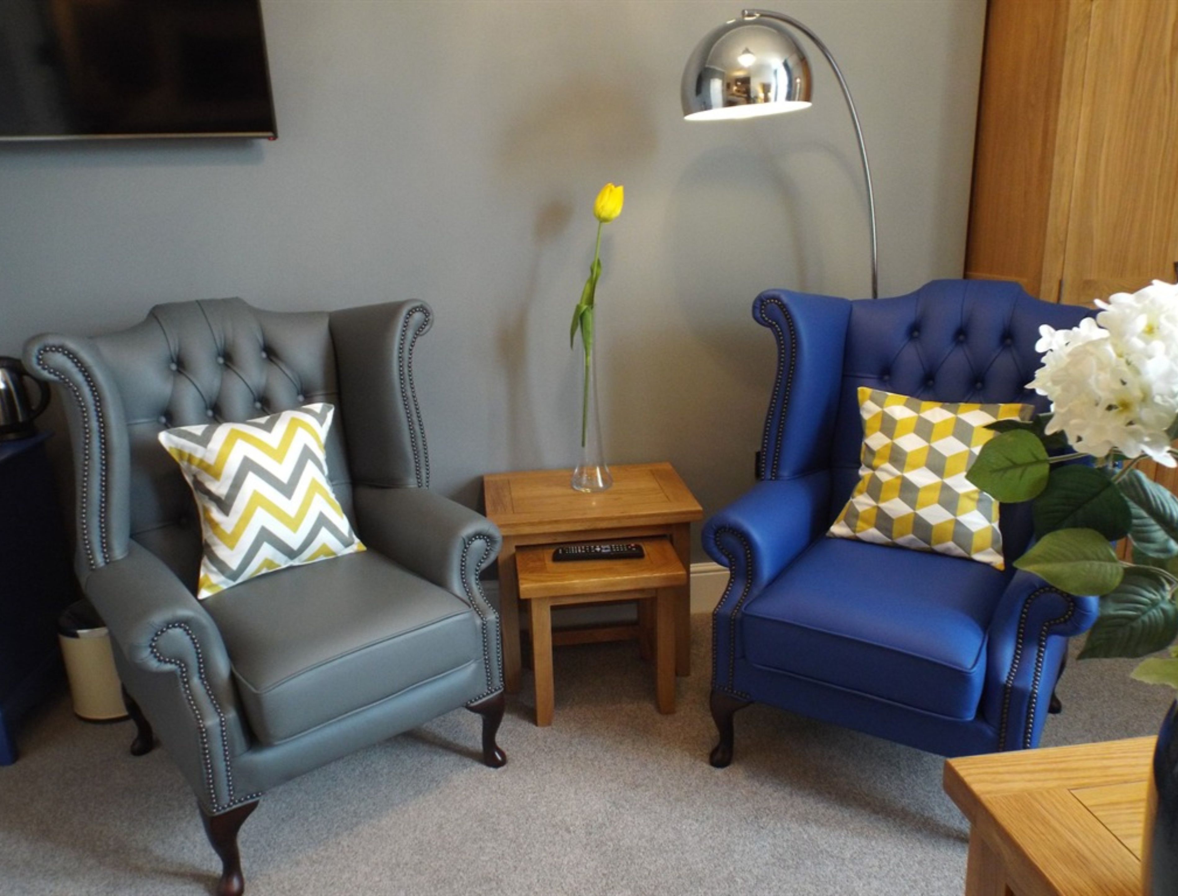 Dos sillones, una mesita de madera y una lámpara de pie en una sala de estar.