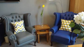 Dos sillones, una mesita de madera y una lámpara de pie en una sala de estar.
