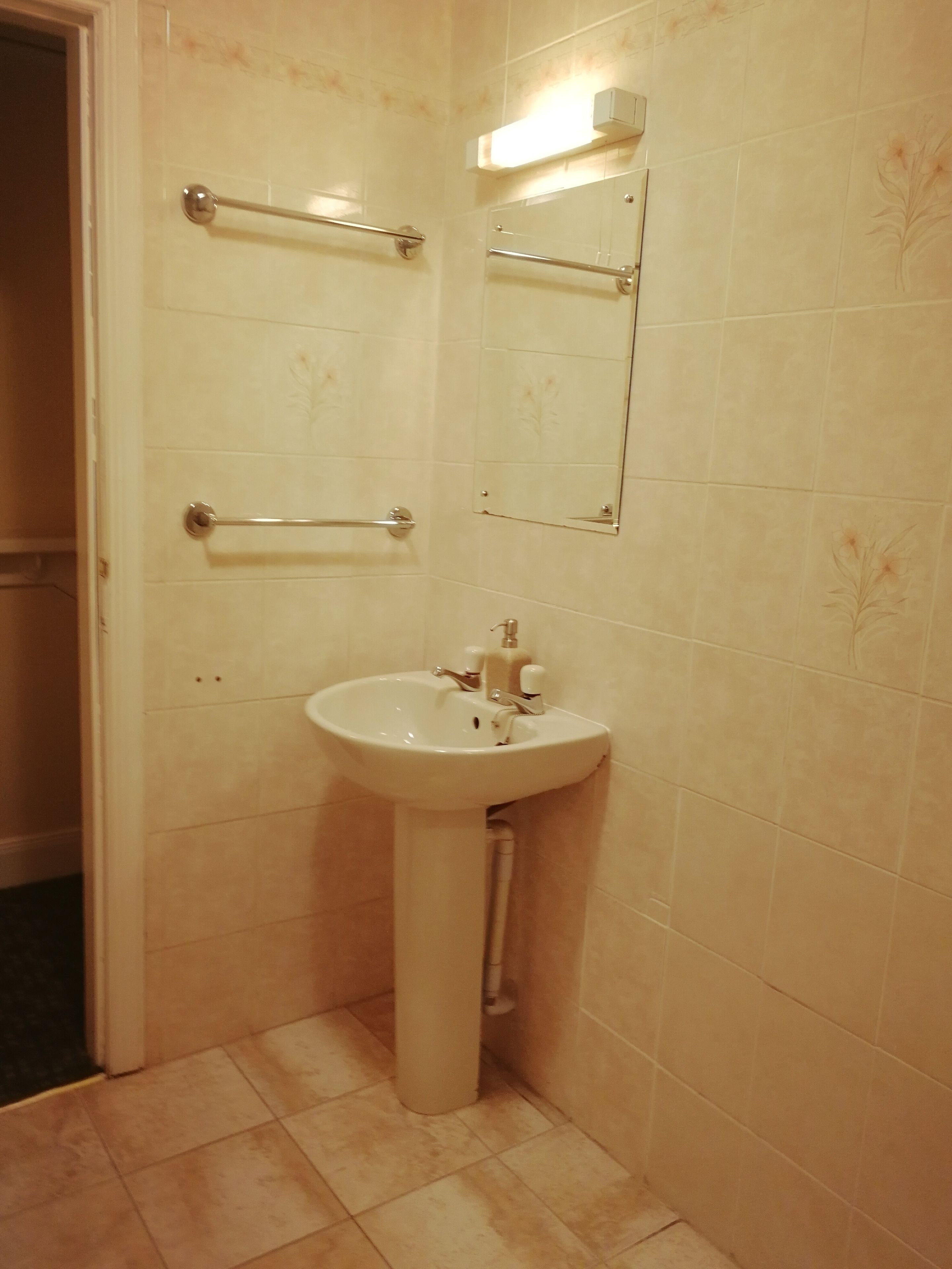 A bathroom with a sink, a mirror, and two towel bars.
