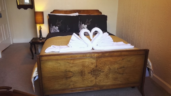 A bed with a wooden headboard and a decorative pillow with floral embroidery. - Victoria Hotel (Blairgowrie)