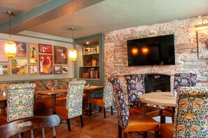 Interior de restaurante con muebles de madera, pared de ladrillo y televisor de pantalla plana sobre la chimenea.