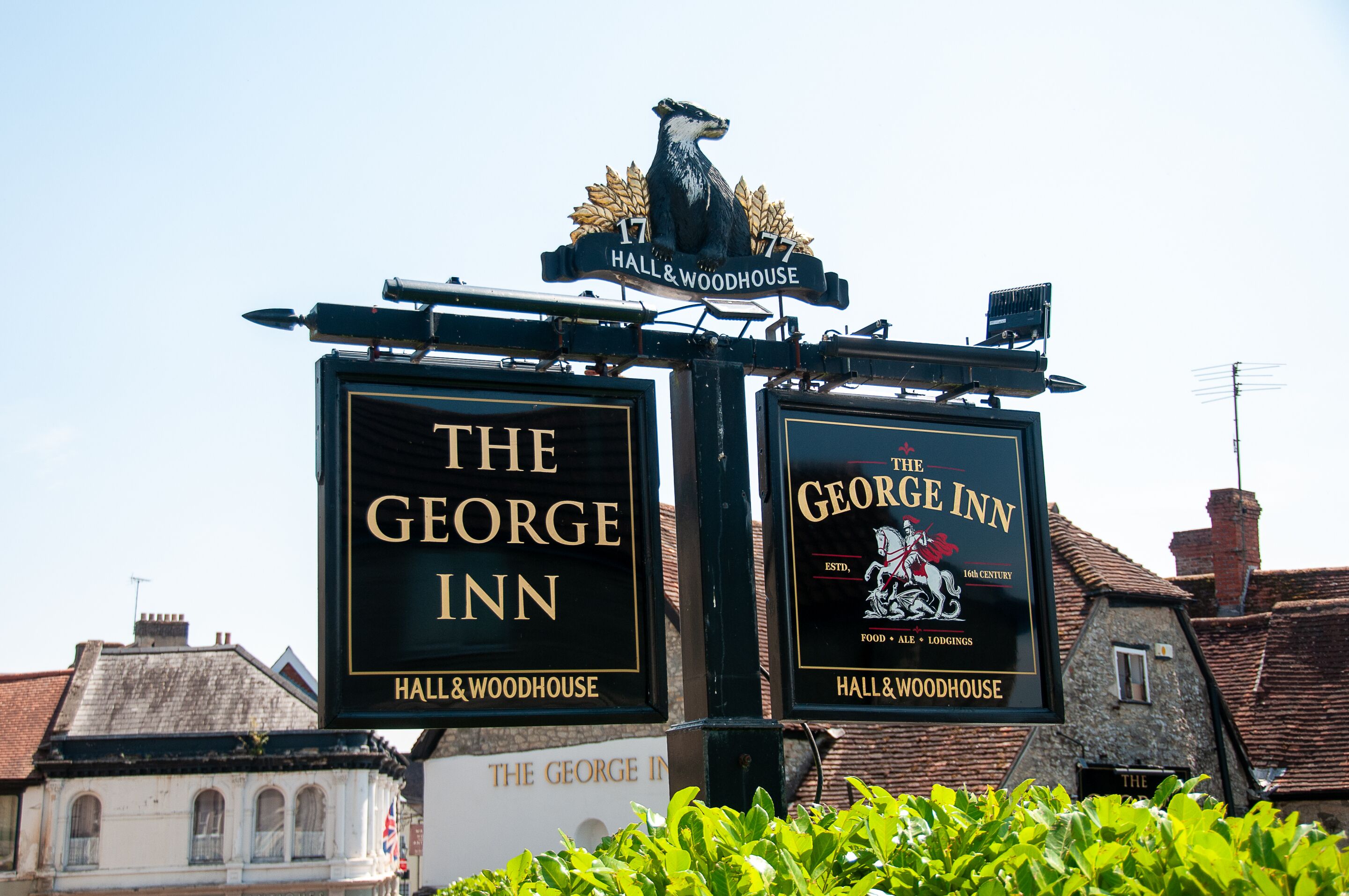 Dos letreros de 'The George Inn' con un emblema de león y el texto 'Hall & Woodhouse'.