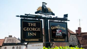 Dos letreros de 'The George Inn' con un emblema de león y el texto 'Hall & Woodhouse'.