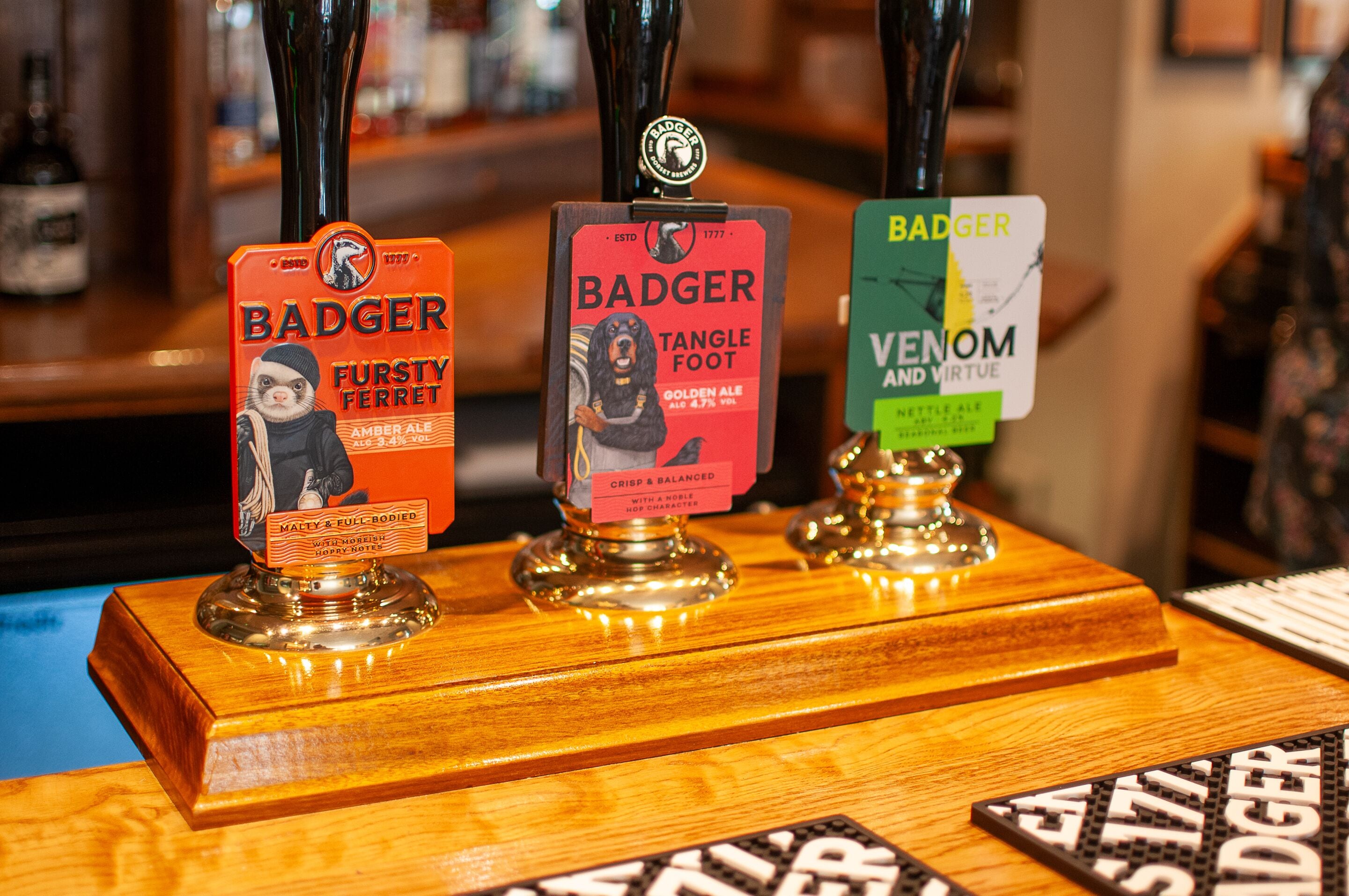 Three beer taps with labels for Badger Furstly Ferret, Badger Tanglefoot, and Badger Venom and Virtue.