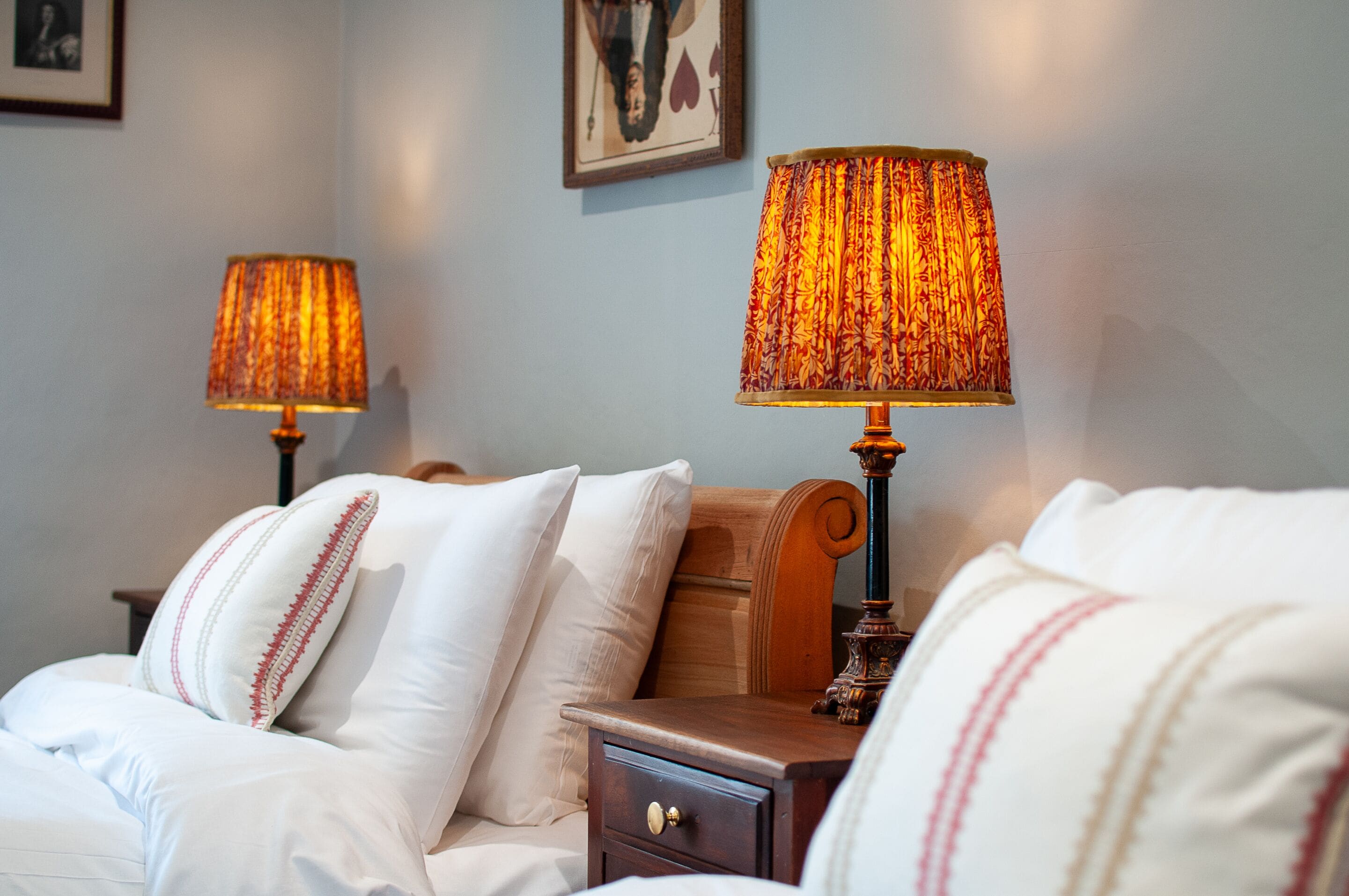 A hotel room with a bed, two bedside lamps, a nightstand, and a framed picture on the wall.