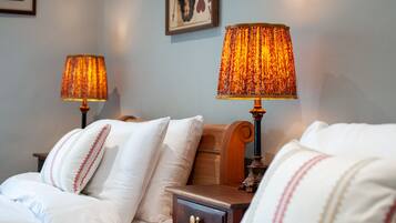 A hotel room with a bed, two bedside lamps, a nightstand, and a framed picture on the wall.