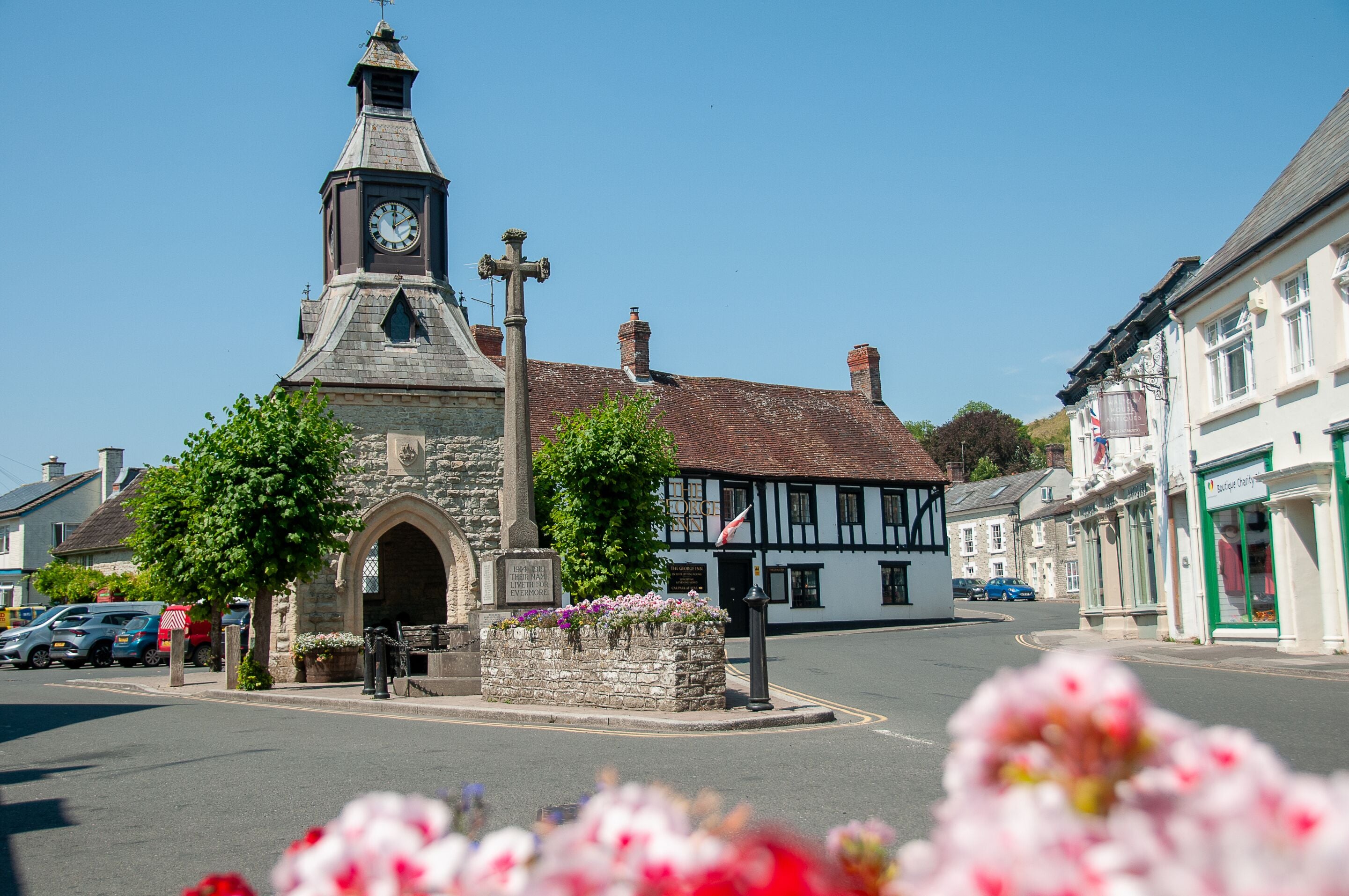 A historic church with a clock tower, a stone archway, and a cross.
