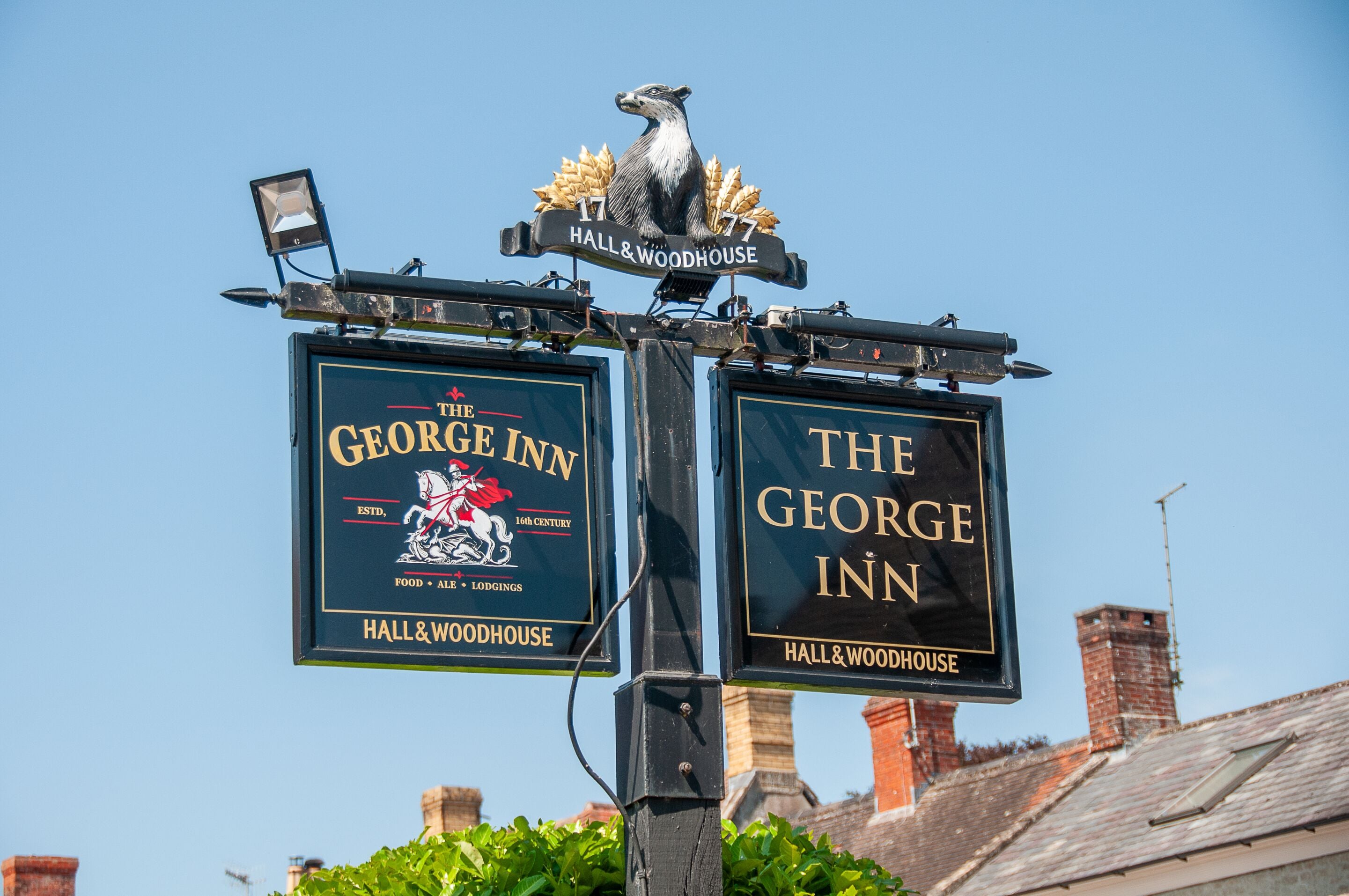 A sign for The George Inn with a crest and establishment date.
