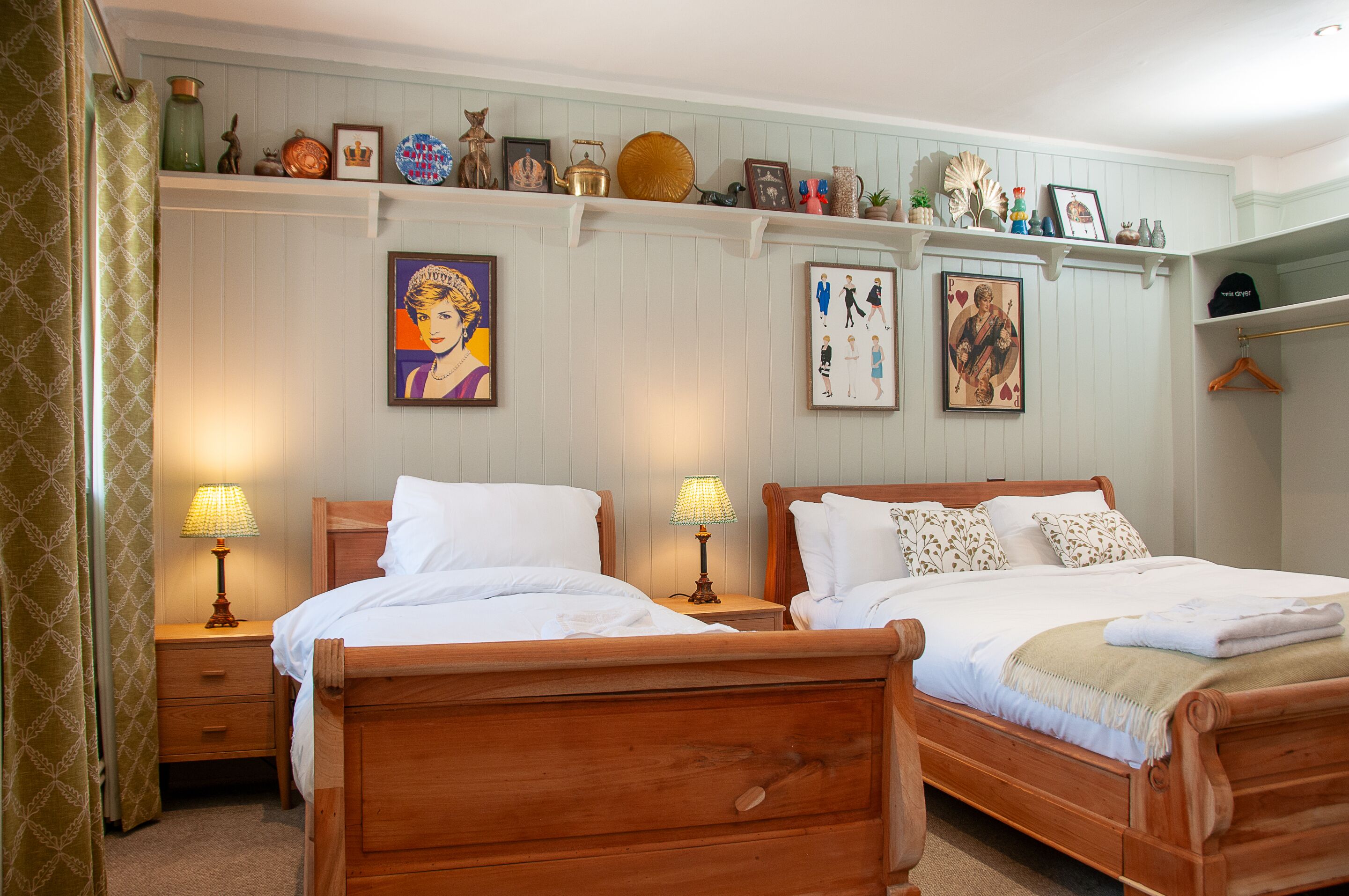 A bedroom with two wooden beds, a dresser, and a shelf with various decorative items.